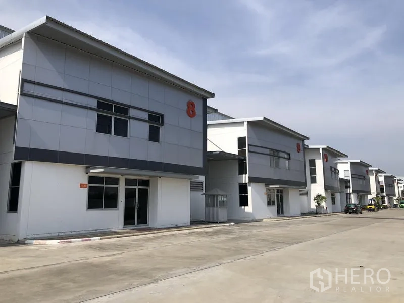 Factory for rent in Phra Nakhon Si Ayutthaya - Row of contemporary factory buildings along a wide internal road with parking.