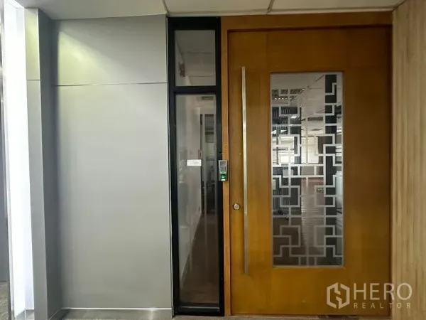 Office Space for rent in Bang Rak, Bangkok - Close-up of the office suite doorway featuring a keypad lock and decorative frosted glass panel in a commercial corridor.