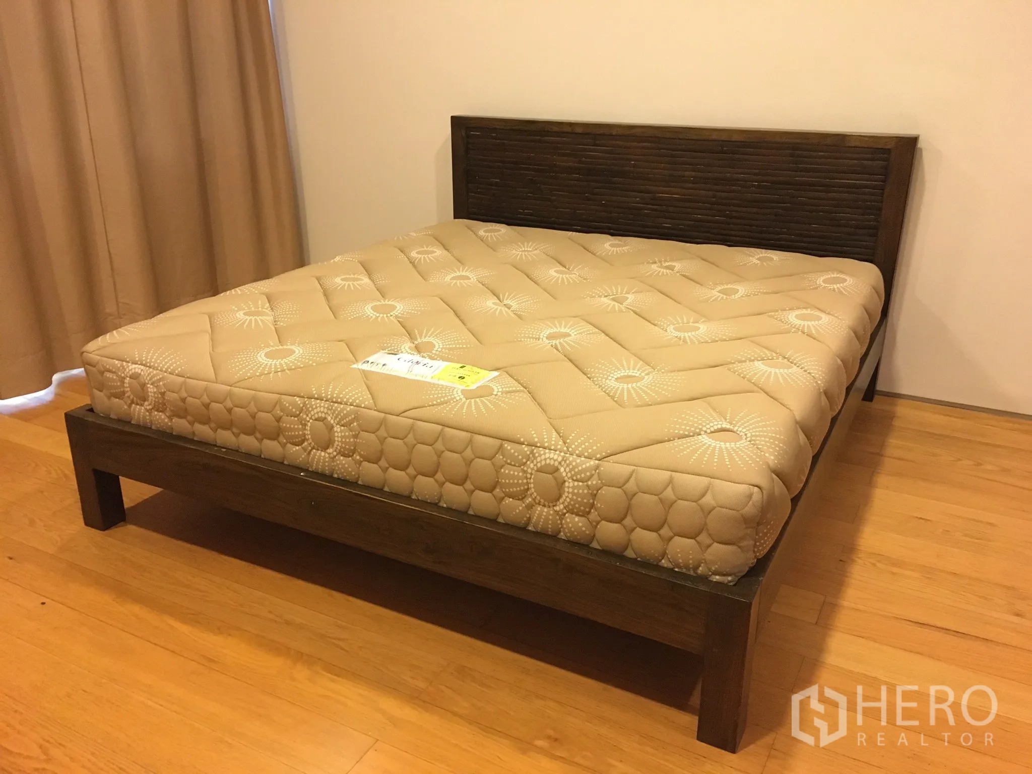 Condominium for rent in Khlong Toei, Bangkok - Cozy bedroom with wooden bed frame and beige mattress.