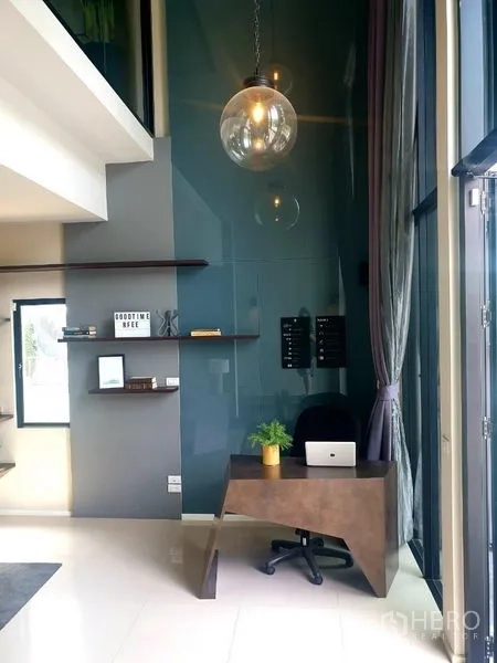 Home Office for rent - Double‑height reception corner with pendant light and front desk by tall windows.