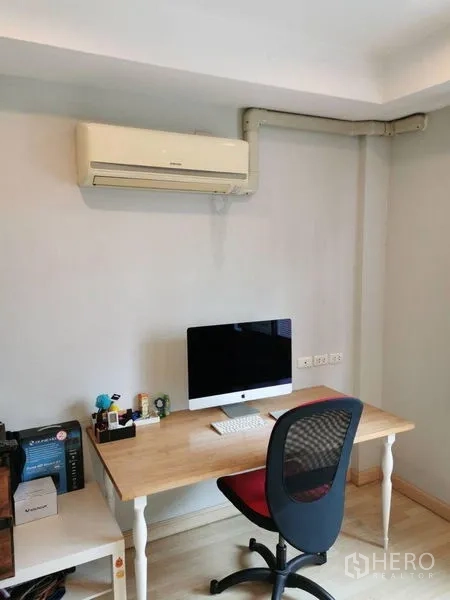 Townhouse for rent or sale in Yan Nawa, Bangkok - Compact home office with wooden desk, desktop computer and wall-mounted air conditioner.