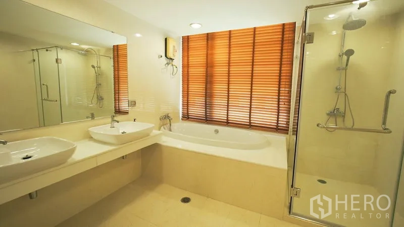 Condominium for rent in Khlong San, Bangkok - Main bathroom featuring double sinks, soaking bathtub, and a glass-enclosed shower.