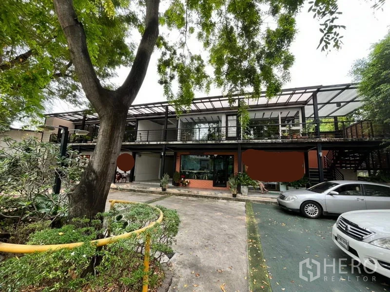 零售空间 出租在Watthana, Bangkok - 两层现代商业楼，整面玻璃立面，设有遮棚步道，绿树成荫并配备停车位，位于曼谷瓦塔那区。