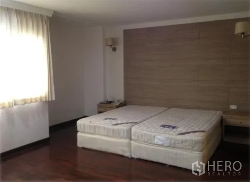 公寓 出租在Watthana, Bangkok - 宽敞卧室，双床垫、织纹床头背景墙与床头柜，采光充足。