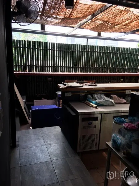 Retail Space for rent in Khlong Toei, Bangkok - Prep and service counter with tiled floor, bamboo privacy screen, and undercounter fridge in the retail space.