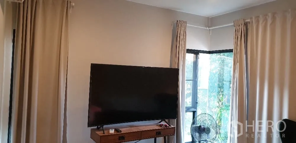 Detached House for rent or sale in Lam Luk Ka, Pathum Thani - TV corner with large flat screen, curtains and window.