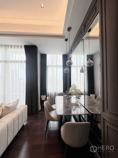 Condominium for rent in Watthana, Bangkok - Elegant dining corner with mirrored wall, marble-top table and three glass pendant lights.