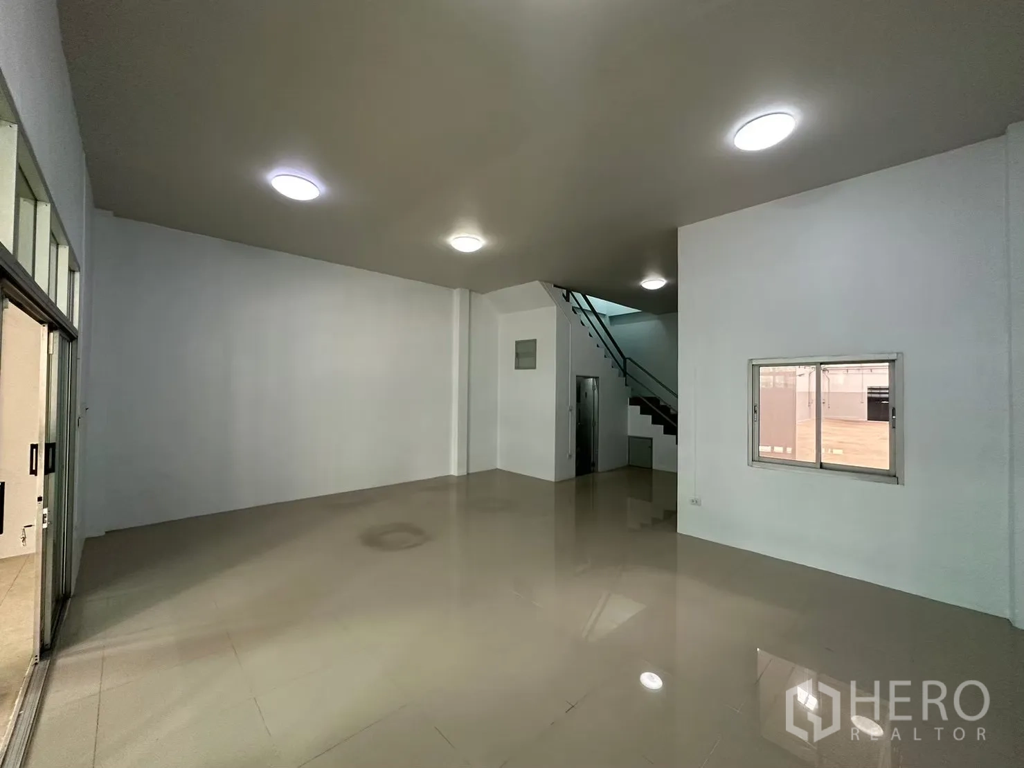 Factory for rent in Bang Bua Thong, Nonthaburi - Spacious tiled ground-floor area with staircase and bright ceiling lights.