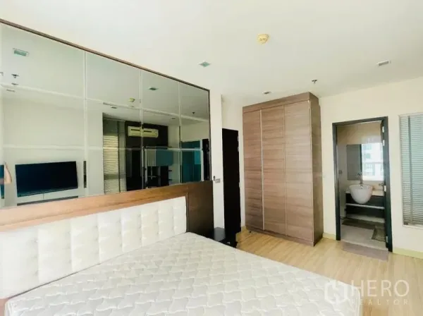 คอนโด ให้เช่า - ห้องนอนกว้างมีผนังกระจก ตู้เสื้อผ้าใบใหญ่ และทางเข้าห้องน้ำ