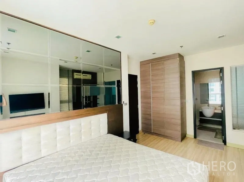 คอนโด ให้เช่า - ห้องนอนกว้างมีผนังกระจก ตู้เสื้อผ้าใบใหญ่ และทางเข้าห้องน้ำ