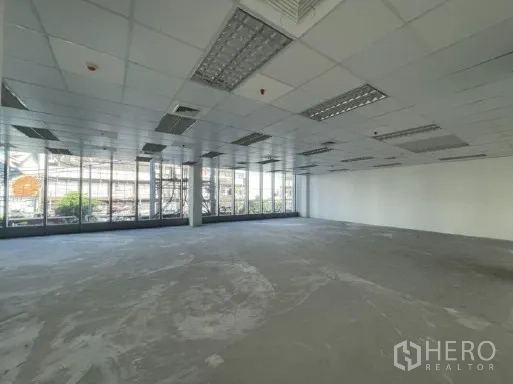 办公空间 出租在Khlong Toei, Bangkok - 开放式办公室，落地窗、格栅吊顶与水泥找平地面。