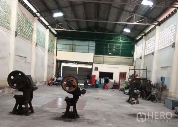 货栈 出租或出售在Pak Kret, Nonthaburi - 宽敞仓库内部，高钢桁架屋顶、玻璃砖通风墙与大型卷闸门。