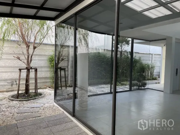 Home Office for rent in Don Mueang, Bangkok - Corner glass walls opening to a landscaped courtyard with stone path and trees.