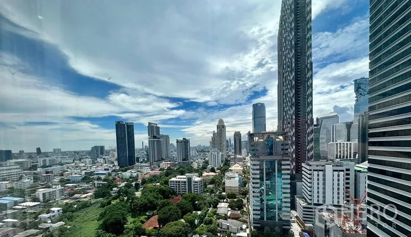 Condominium for rent - High-rise skyline view over Sathon and Silom with towers and green spaces under a blue sky.