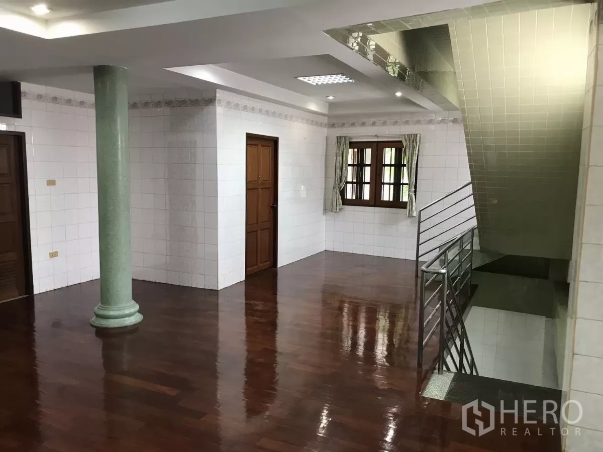Home Office for rent in Dusit, Bangkok - Bright landing area with wooden floors, a green column, and a stairwell with metal handrail.
