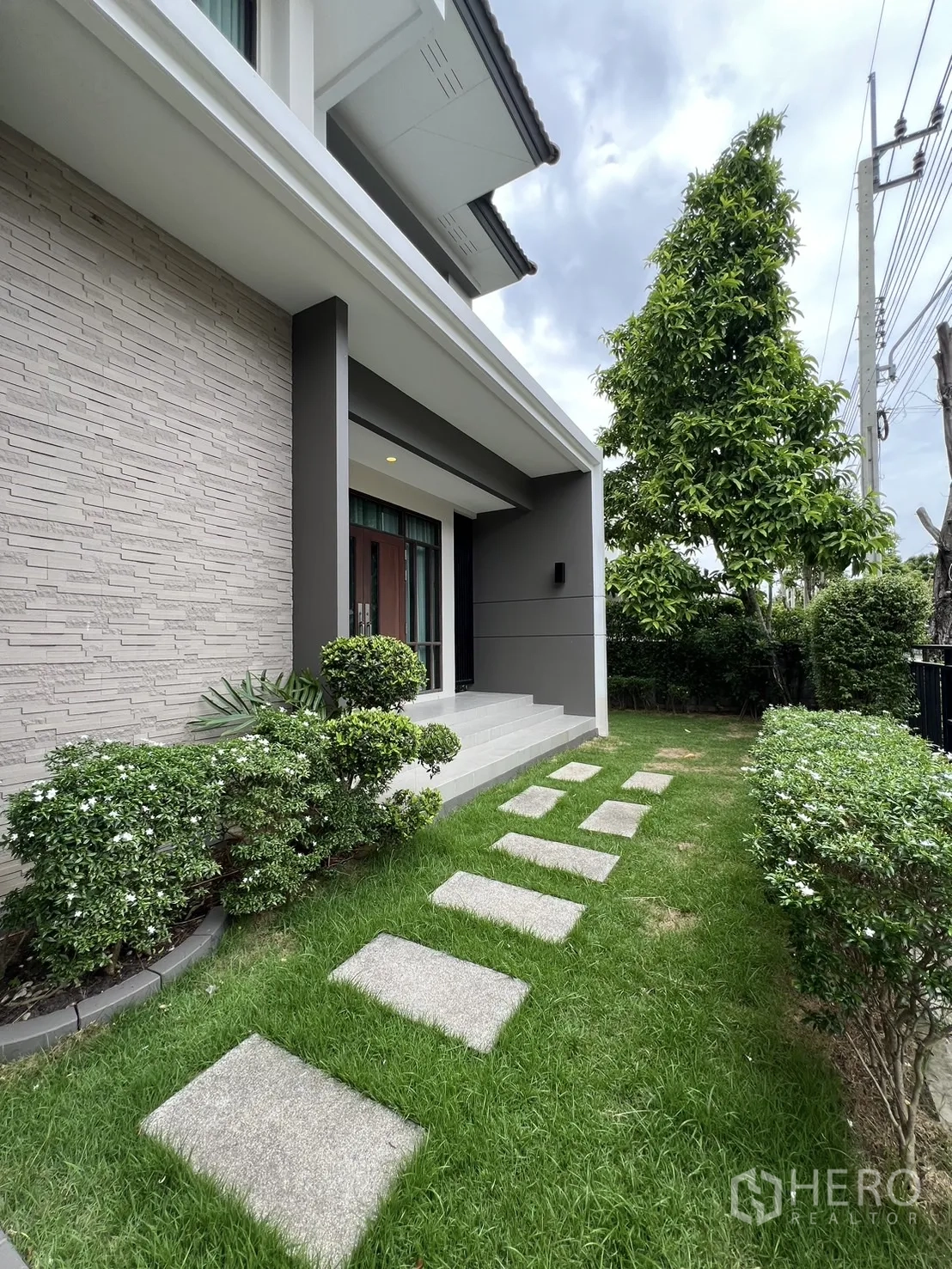 Detached House for rent or sale in Prawet, Bangkok - Front garden with stepping stones, manicured shrubs and a porch.