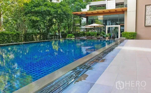公寓 出租在Pathum Wan, Bangkok - 公寓室外蓝色瓷砖泳池，设日光甲板与绿化，位于曼谷帕吞旺。