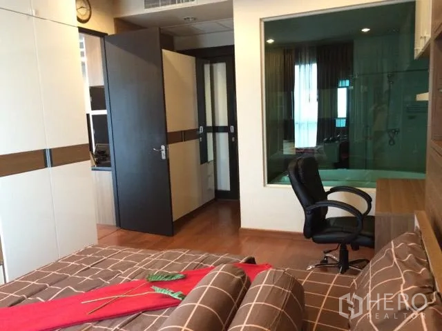 公寓 出租在Pathum Wan, Bangkok - 主卧带书桌与嵌入式衣柜，并有与浴室相连的玻璃隔窗。