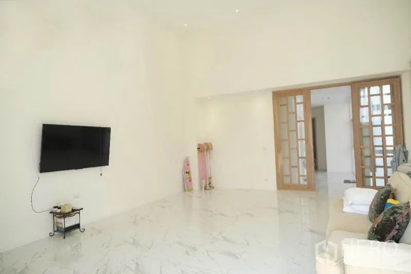 带办公室的家 出租或出售在Prawet, Bangkok - 宽敞客厅，墙装电视、木质推拉门与亮面地砖。