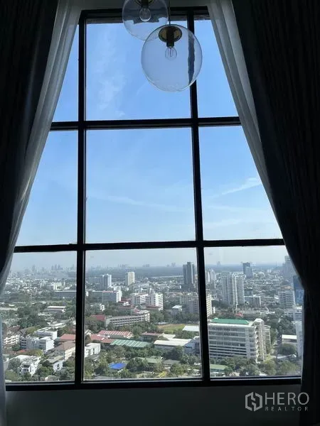 คอนโด ให้เช่าในSathon, Bangkok - วิวสกายไลน์กรุงเทพฯ ผ่านหน้าต่างสูงพร้อมผ้าม่านโปร่งในวันฟ้าใส