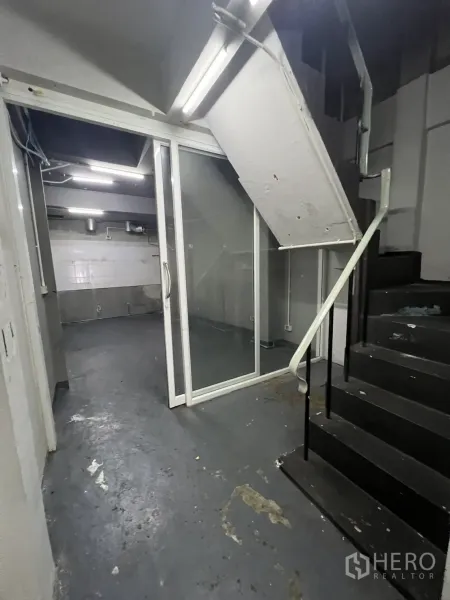 Shophouse for rent in Watthana, Bangkok - Rear service area with black staircase and glass sliding door.