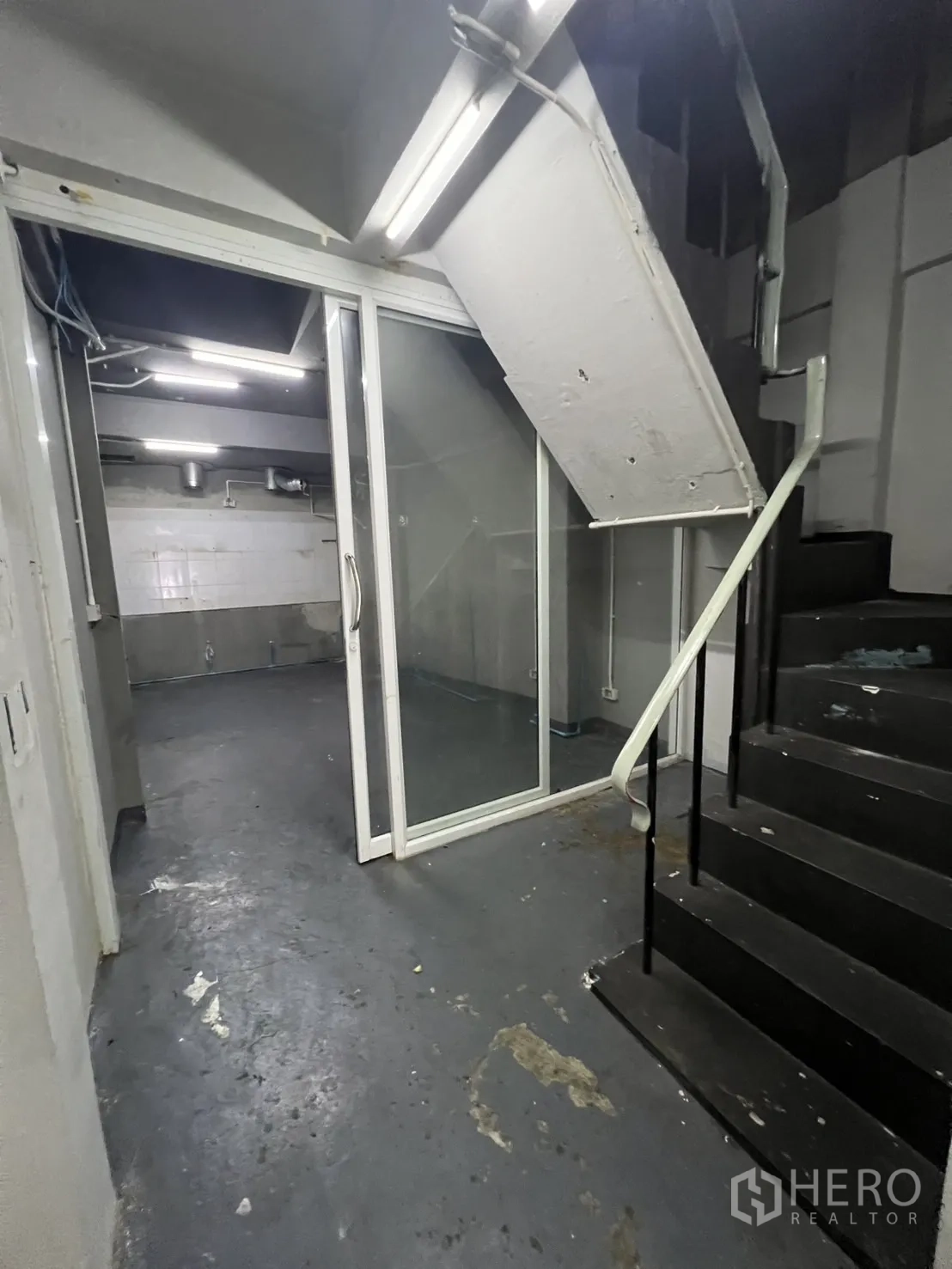 Shophouse for rent in Watthana, Bangkok - Rear service area with black staircase and glass sliding door.