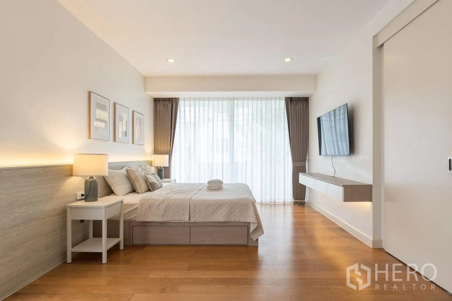 Detached House for rent in Saphan Sung, Bangkok - Spacious bedroom with king bed, wall-mounted TV, and floor-to-ceiling curtains.