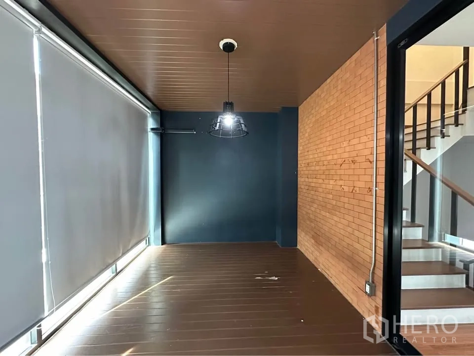 联排别墅 出租在Pak Kret, Nonthaburi - 工业风走廊，裸露砖墙，邻近楼梯与遮光帘。