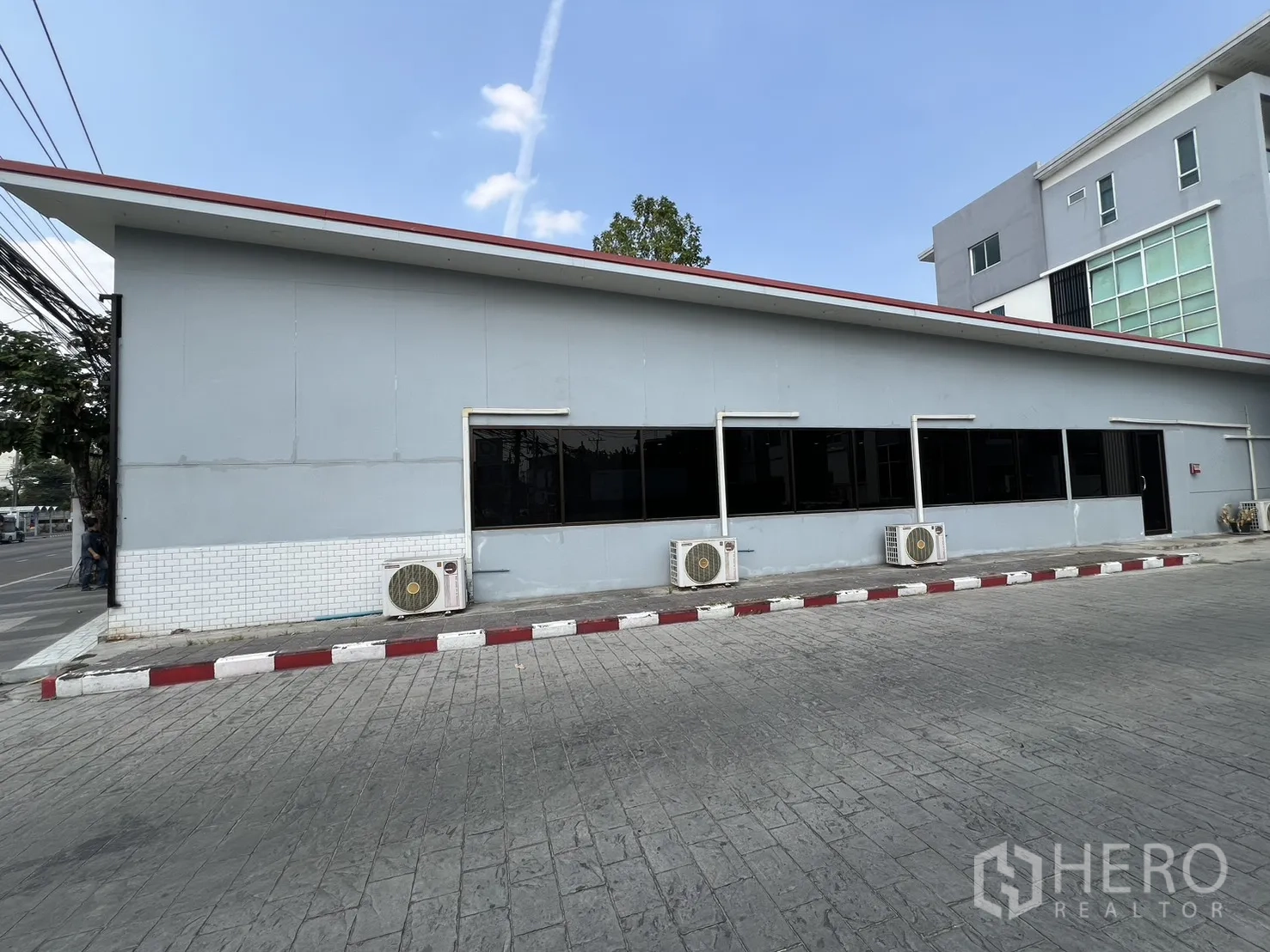 零售空间 for rent in Bueng Kum, Bangkok - 建筑侧立面，一排窗户与外机，旁有车道停车区。
