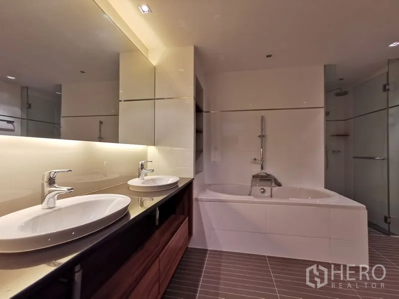 Condominium for rent or sale in Phaya Thai, Bangkok - Bathroom view showing illuminated mirror, twin sinks, and deep bathtub.