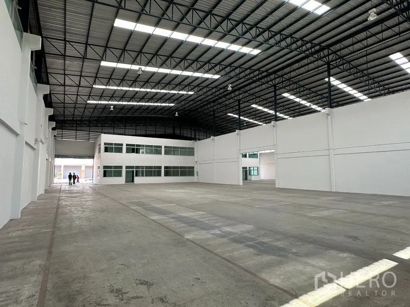 Warehouse for rent in Mueang Samut Prakan, Samut Prakan - Expansive warehouse interior facing the mezzanine office block under a tall roof.
