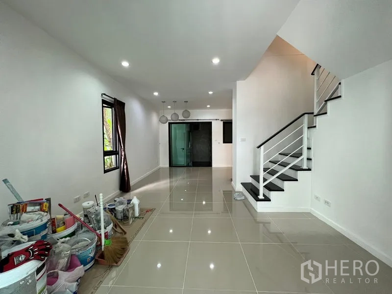 Townhouse for sale in Bang Kapi, Bangkok - Long open-plan living and dining area with glossy tile floor and stairs.