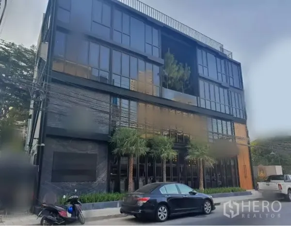 Retail Space for rent in Khlong Toei, Bangkok - Modern black‑glass commercial building with street frontage and palm landscaping.