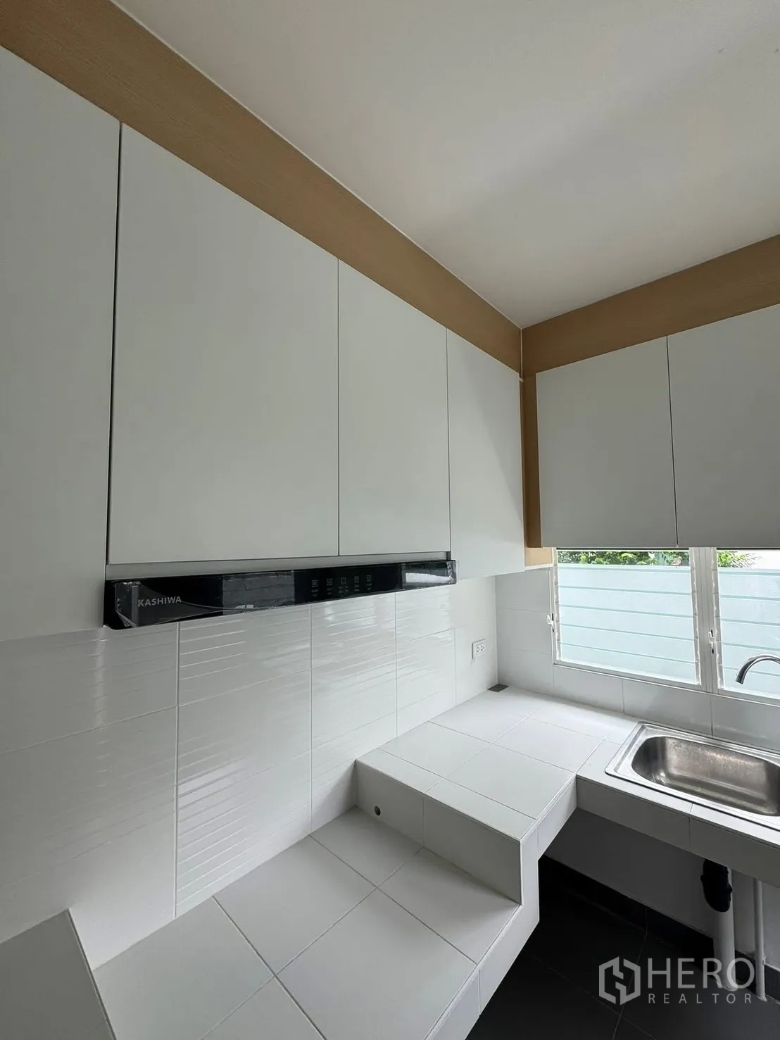 Detached House for rent in Bang Phli, Samut Prakan - Bright kitchen with white cabinets, tiled counters, and sink by the window.
