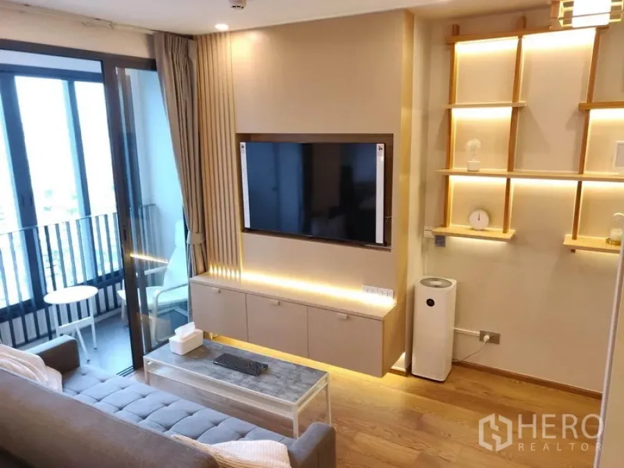 公寓 出租在Ratchathewi, Bangkok - 电视墙配悬空柜与氛围灯，滑门通往带座椅的阳台。
