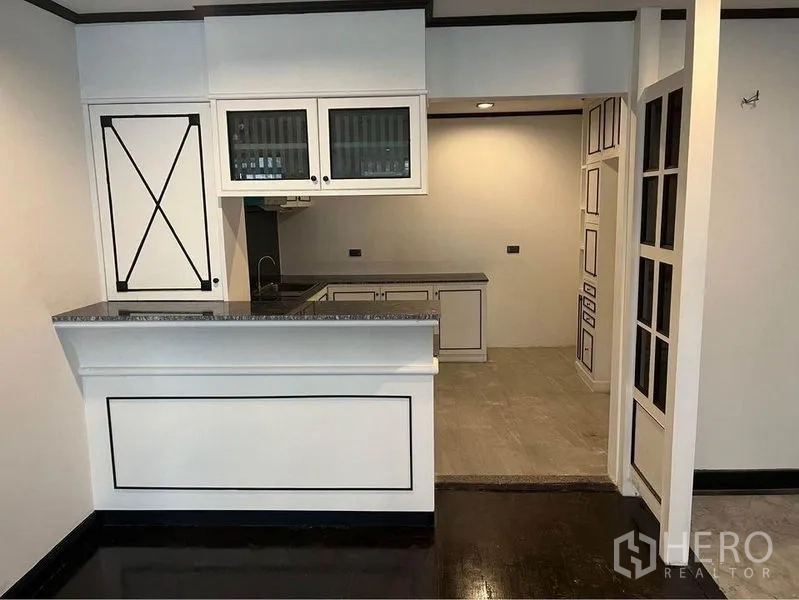 Condominium for rent or sale in Watthana, Bangkok - Kitchen pass-through and breakfast counter beside glass-panel door.