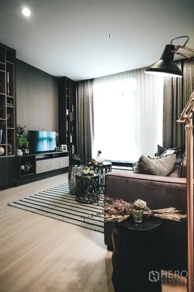 คอนโด ให้เช่าในHuai Khwang, Bangkok - ห้องนั่งเล่นอบอุ่น หน้าต่างบานใหญ่ ตู้บิลท์อิน โซฟา พรมลายเส้น และโต๊ะกลางซ้อน