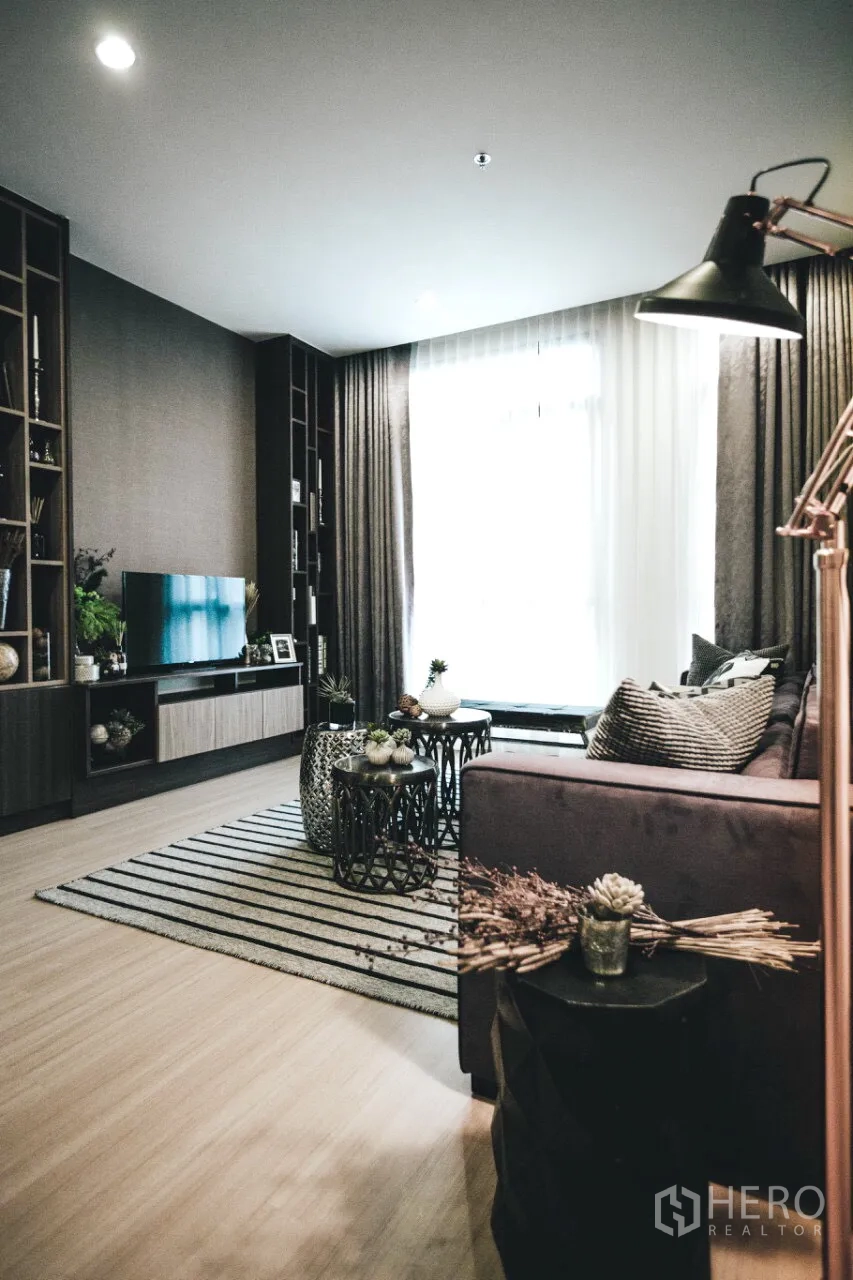 คอนโด ให้เช่าในHuai Khwang, Bangkok - ห้องนั่งเล่นอบอุ่น หน้าต่างบานใหญ่ ตู้บิลท์อิน โซฟา พรมลายเส้น และโต๊ะกลางซ้อน