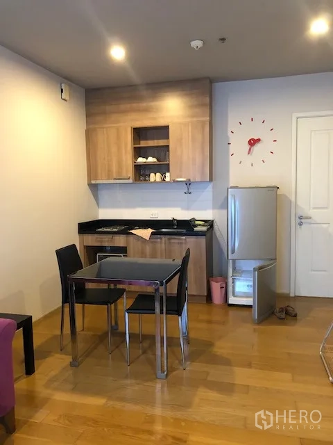 公寓 出租在Khlong San, Bangkok - 公寓小厨房，木质橱柜、双人餐桌、冰箱与木地板。