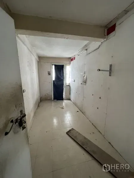 Shophouse for rent in Watthana, Bangkok - Empty rectangular room with white walls and tiled floor awaiting renovation, with a rear doorway and light.