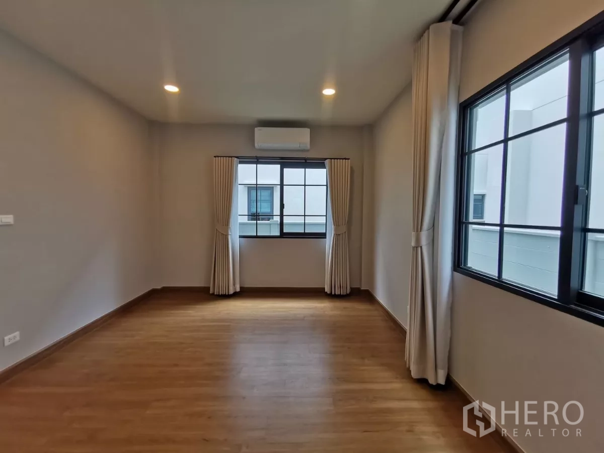 Detached House for rent in Bang Phli, Samut Prakan - Empty bedroom space with wood flooring and large windows.