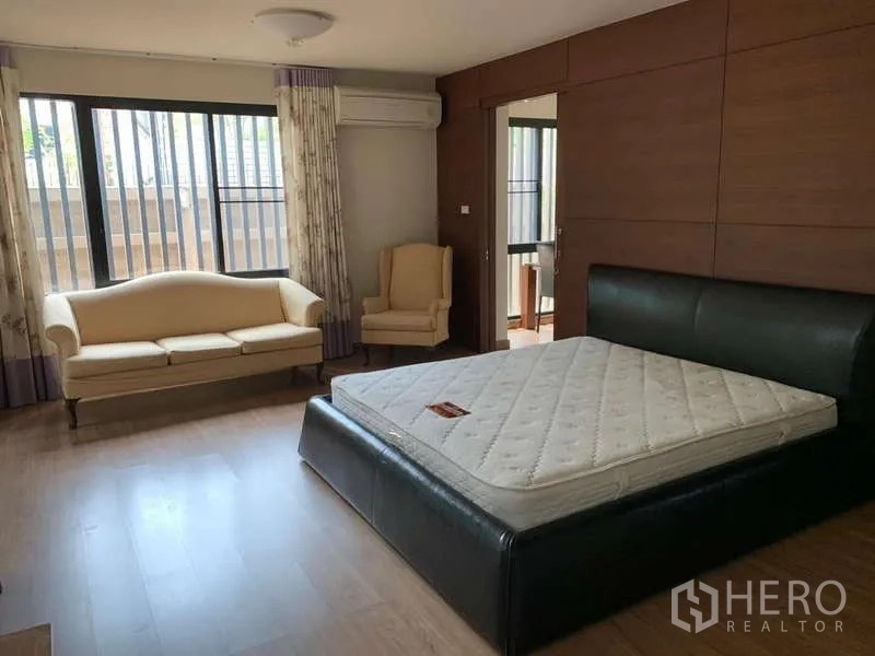 独立式住宅 出租 - 主卧配皮床、沙发休闲区、大窗与木质装饰墙。
