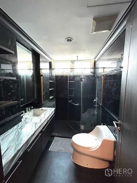公寓 出售在Watthana, Bangkok - 现代卫浴，配大理石台盆、深色瓷砖与玻璃淋浴间。