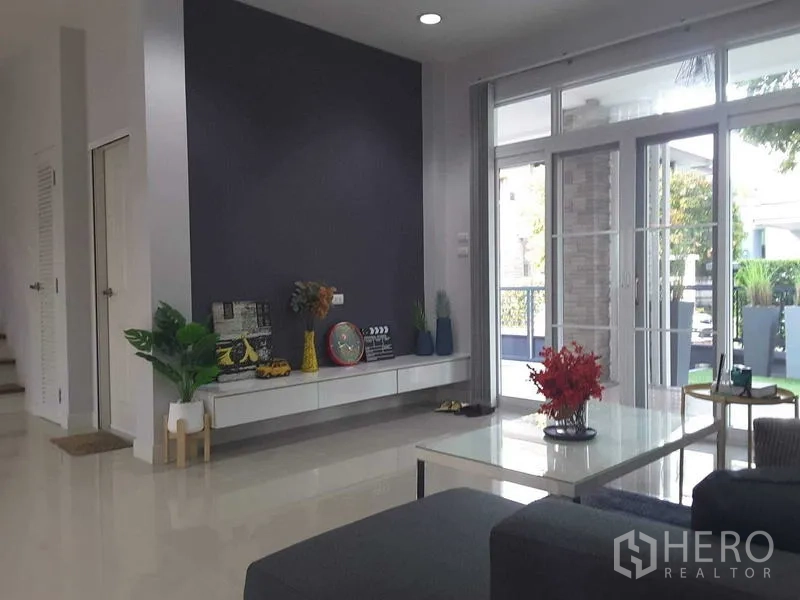 Detached House for rent in Lam Luk Ka, Pathum Thani - Living room facing sliding glass doors to the garden with a floating TV shelf.