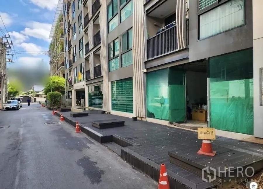 零售空间 出租 - 建筑沿静街立面，路边有锥筒与多间店铺门面。