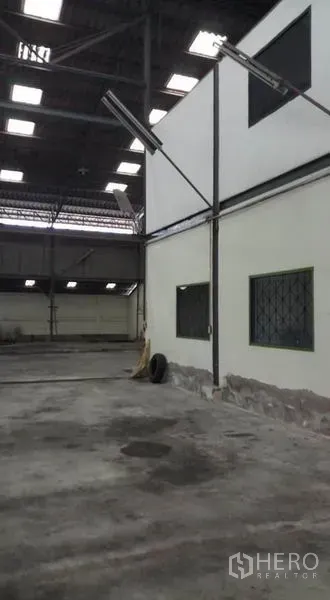 Warehouse for rent in Bang Phli, Samut Prakan - Interior corner with partitioned office windows and concrete floor.