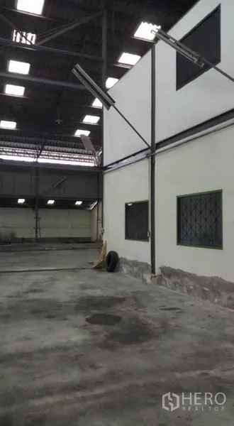 Warehouse for rent in Bang Phli, Samut Prakan - Interior corner with partitioned office windows and concrete floor.