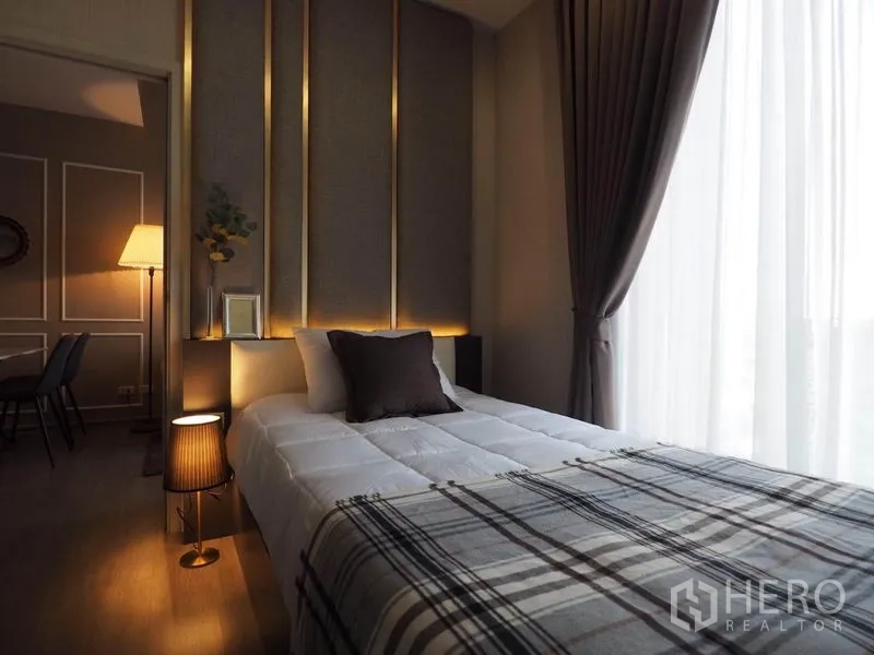 Condominium for rent in Khlong San, Bangkok - Cozy bedroom with padded feature wall, warm lighting, and floor-to-ceiling window.