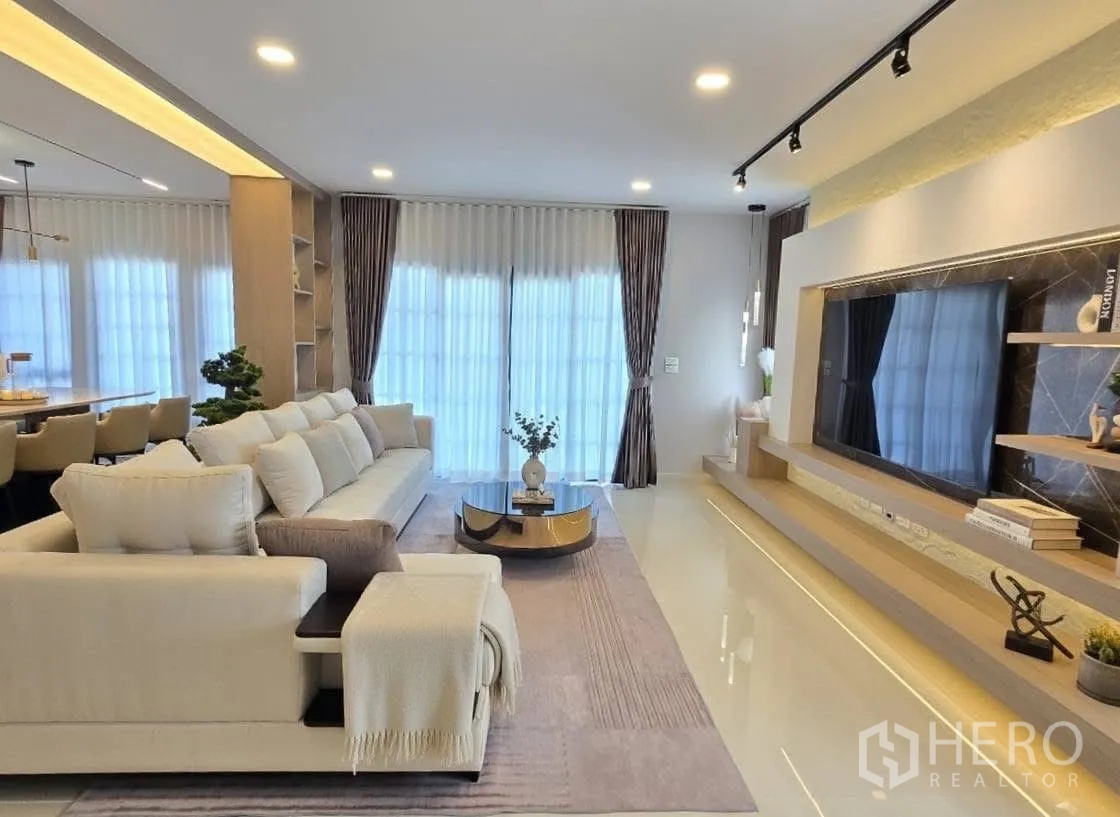 Detached House for rent or sale in Bang Phli, Samut Prakan - Living lounge with long sectional sofa, coffee table and floor‑to‑ceiling glazing.