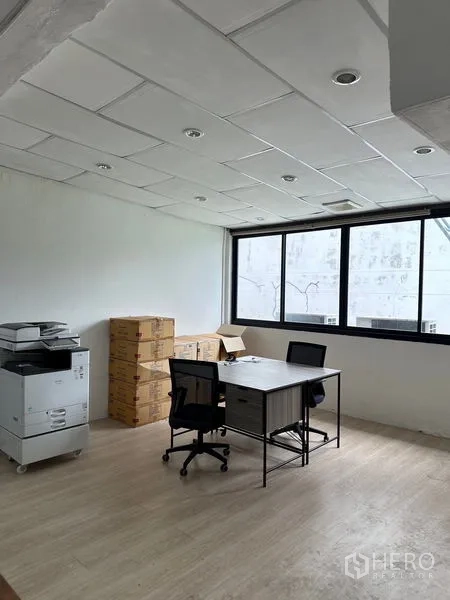 Shophouse for rent in Khlong Toei, Bangkok - Bright office room with two desks, a printer and storage boxes beside a wide window.